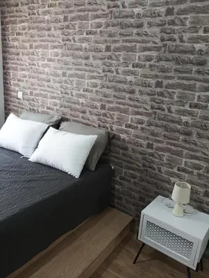 a bedroom with a brick wall and a bed and a table at Βιργινία κοντα σε μετρο πανορμου και σε νοσοκομεια in Athens