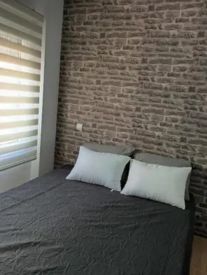 a bedroom with a brick wall and a bed with two pillows at Βιργινία κοντα σε μετρο πανορμου και σε νοσοκομεια in Athens