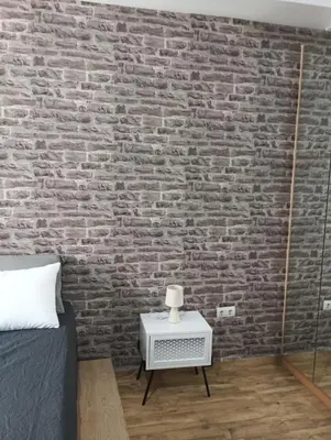 a bedroom with a brick wall with a bed and a night stand at Βιργινία κοντα σε μετρο πανορμου και σε νοσοκομεια in Athens