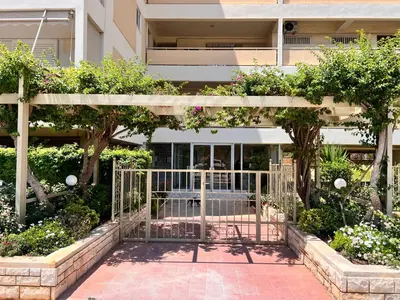 a gate in front of a building with trees and flowers at Krystalli 3BR apartment in Voula by ΜΡS in Athens