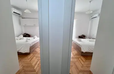 two beds in a room with white walls and wood floors at Krystalli 3BR apartment in Voula by ΜΡS in Athens