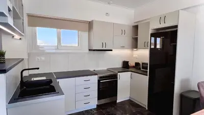 a kitchen with white cabinets and a black refrigerator at Krystalli 3BR apartment in Voula by ΜΡS in Athens