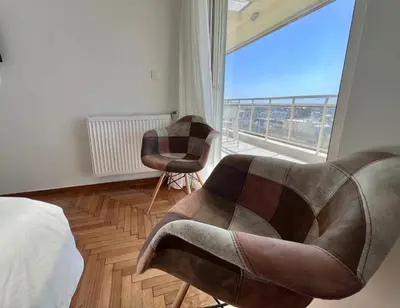 a bedroom with a chair and a large window at Krystalli 3BR apartment in Voula by ΜΡS in Athens