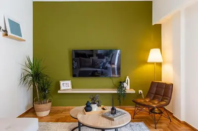 a living room with a green wall with a table and chairs at Eleni's Terrace in Ampelokipi in Athens