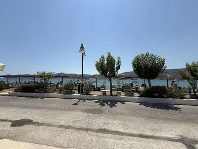 a empty street with trees and tables and a beach at SeaWave Porto Rafti in Porto Rafti