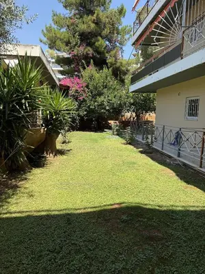a yard in front of a building with green grass at SeaWave Porto Rafti in Porto Rafti