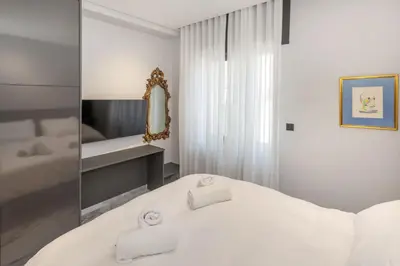 a white bedroom with a bed and a mirror at Syntagma Acropolis M5 in Athens