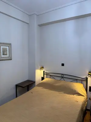 a bedroom with a bed in a white room at Cozy vintage flat in Athens
