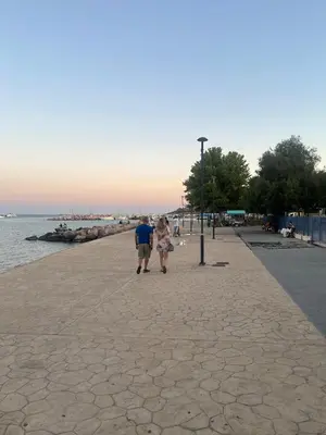 a man and woman walking down a sidewalk next to the water at Varkiza Beach Entire Apartment in Vari