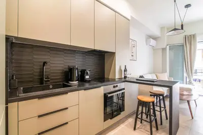 a kitchen with white cabinets and a black counter top at A43 Renovated in 2025 Great base for Koukaki in Athens