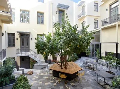 a courtyard with a tree and tables and chairs at InnAthens in Athens