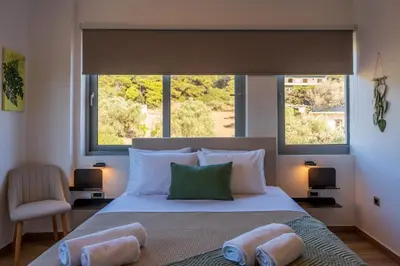 a bedroom with a large bed with two large windows at AK-Green Villa near Athens Airport in Vravrona