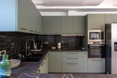 a kitchen with white cabinets and stainless steel appliances at AK-Green Villa near Athens Airport in Vravrona