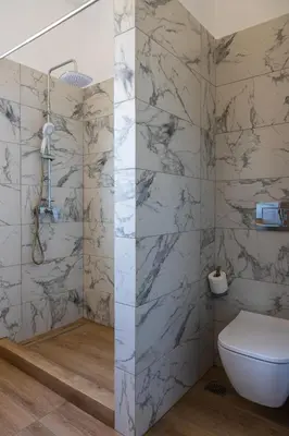 a bathroom with a white toilet and marble walls at AK-Green Villa near Athens Airport in Vravrona