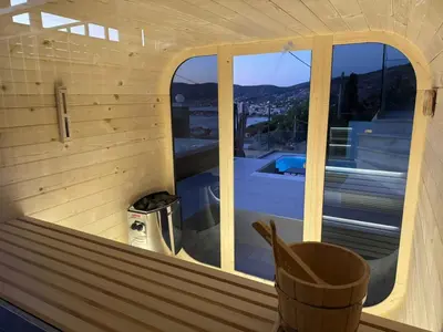 a wooden sauna with a view of a swimming pool at Helios Apartments Porto Rafti in Porto Rafti