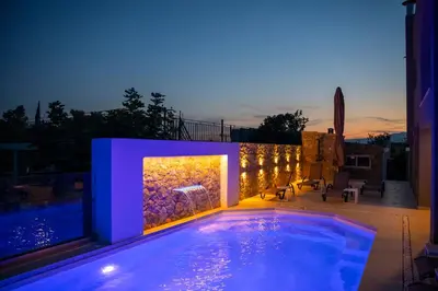 a large swimming pool with a lit up wall at Helios Apartments Porto Rafti in Porto Rafti