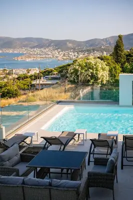 a swimming pool with chairs and a table next to it at Helios Apartments Porto Rafti in Porto Rafti
