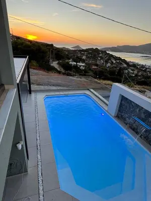 a blue swimming pool on top of a house at Helios Apartments Porto Rafti in Porto Rafti