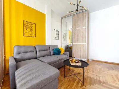 a living room with a couch and a yellow wall at Studio Σταθμός Λαρίσης 100Mbps , Μπαλκόνι in Athens