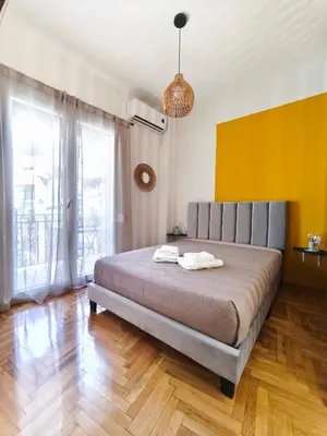 a bedroom with a large bed with a yellow wall at Studio Σταθμός Λαρίσης 100Mbps , Μπαλκόνι in Athens
