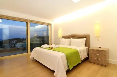 a bedroom with a large bed and a large window at Villa Nelmar in Anavissos
