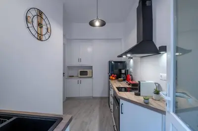 a kitchen with white cabinets and a clock on the wall at Archive, The Art of Living in Athens