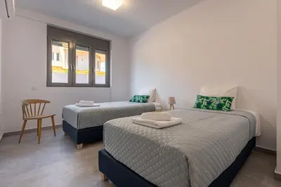 a bedroom with two beds and a chair and a window at Φωτεινό σπίτι 200μ από την παραλία in Porto Rafti