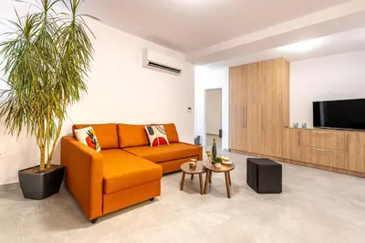 a living room with a orange couch and a tv at Φωτεινό σπίτι 200μ από την παραλία in Porto Rafti