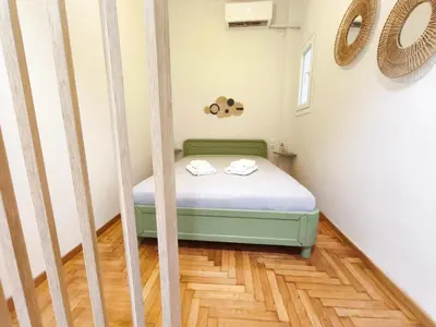 a bed in a room with a wooden floor at Cosy apartment next to Larissa station 100Mbps & Balcony in Athens