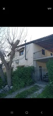 a white building with a balcony and a tree at Pallini house in Pallíni