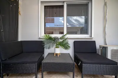 two chairs and a table with a plant on a porch at Lilac Dream in Glyfada by ΜΡS in Athens