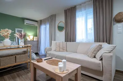 a living room with a white couch and a table at Boho Nest in Glyfada by ΜΡS in Athens