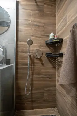 a shower in a bathroom with a wooden wall at Boho Nest in Glyfada by ΜΡS in Athens