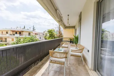 a balcony with a table and chairs and a window at Raise Coastal Grand Escape in Athens