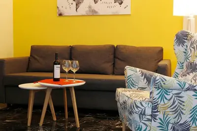 a couch and two glasses of wine on a table at The Brightline Apartment Athens in Athens