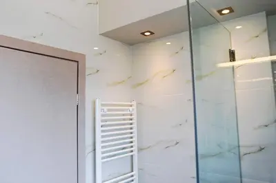 a bathroom with a glass shower and a ladder at The Brightline Apartment Athens in Athens