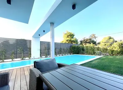 a patio with a table and a swimming pool at Athens Riviera, 2 Pools & Gym Luxury Residence 310m2 in Athens