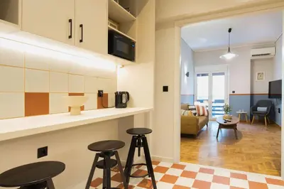 a kitchen with two bar stools and a living room at Acropolis Luxury retreat in Athens