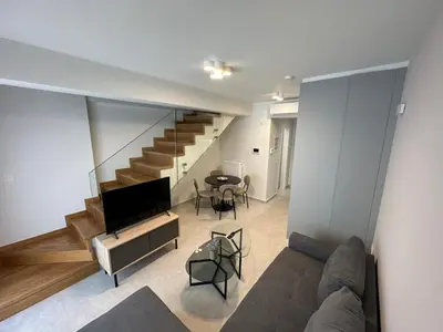 a living room with a couch and a table and stairs at Niarchos Elegant Maisonette in Athens