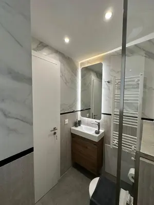 a white bathroom with a sink and a mirror at Niarchos Elegant Maisonette in Athens