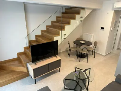 a living room with a television and a table with chairs at Niarchos Elegant Maisonette in Athens