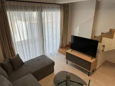 a living room with a couch and a flat screen tv at Niarchos Elegant Maisonette in Athens
