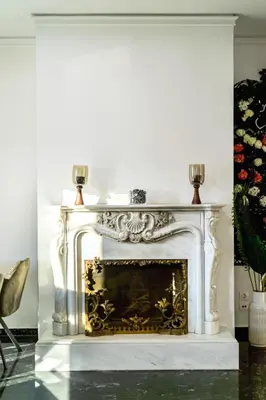 a white fireplace in a living room with a chair at Traveler's Dream 3-Bedroom Renovated Penthouse in Athens