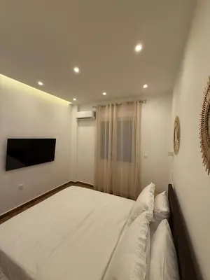 a white bedroom with a large bed and a tv at Byron cozy brand new apartment in Athens