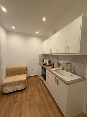 a kitchen with white cabinets and a sink and a table at Byron cozy brand new apartment in Athens