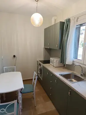 a kitchen with green cabinets and a sink and a table at Athens Royal Suite in Athens