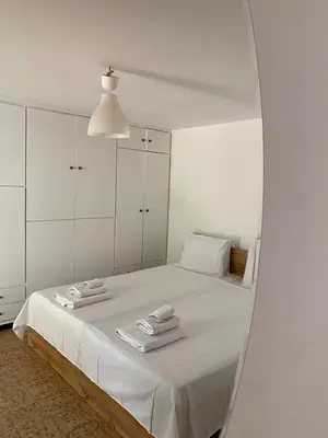 a white bedroom with a bed with a mirror at Glyfada Charm, Cozy & Warm with private parking in Athens