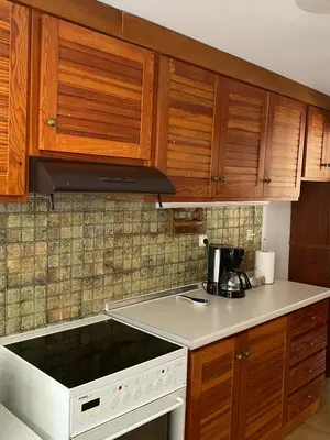 a kitchen with wooden cabinets and a white stove top oven at Glyfada Charm, Cozy & Warm with private parking in Athens