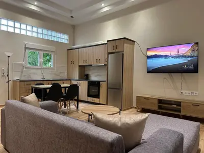 a living room with a couch and a tv on the wall at Διαμέρισμα κοντά στο μετρό - Flat next to metro in Piraeus