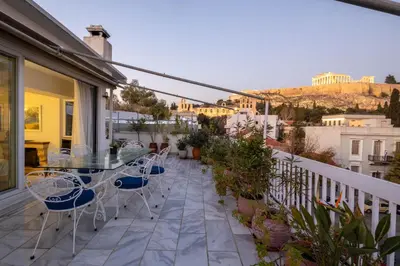 a patio with a glass table and chairs on a balcony at Massive 2 Apartment Combo Unbeatable Acropolis Views Sleeps 9 in Athens